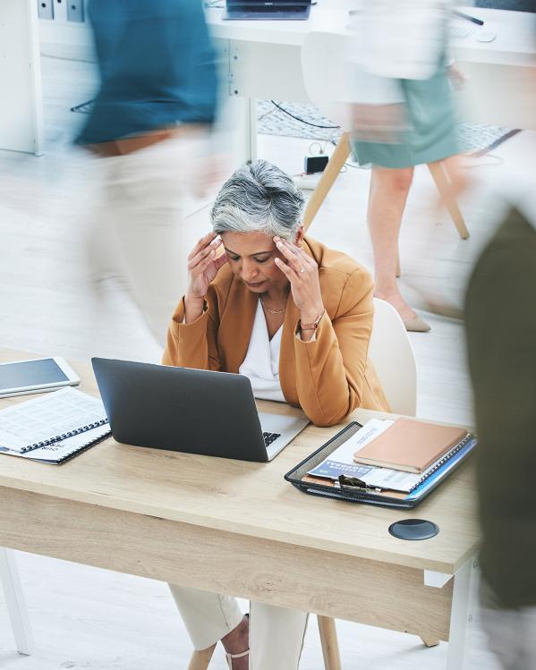 vrouw op kantoor is overprikkeld en grijpt naar haar hoofd