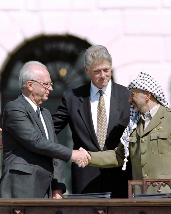 Rabin en Arafat schudden de hand, Clinton staat erachter
