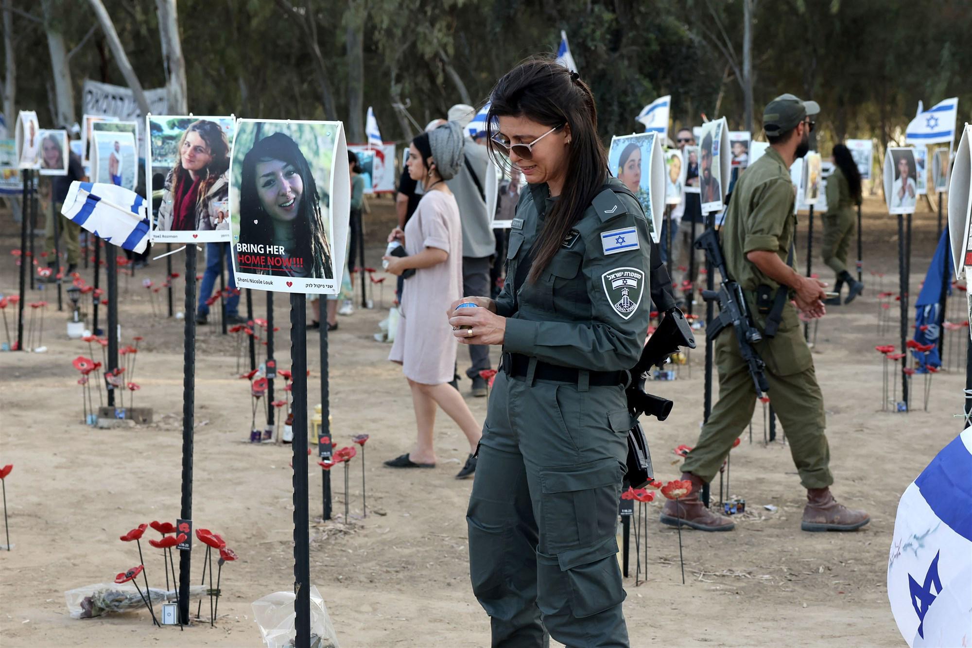 Iemand van de Israëlische security forces staat bij portretten van slachtoffers van de aanval