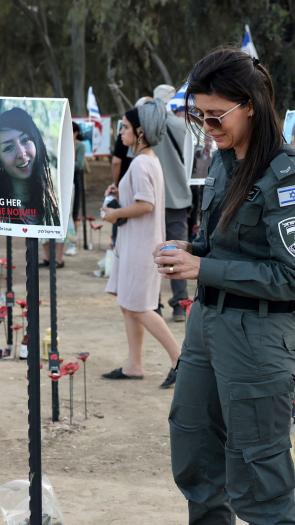 Iemand van de Israëlische security forces staat bij portretten van slachtoffers van de aanval