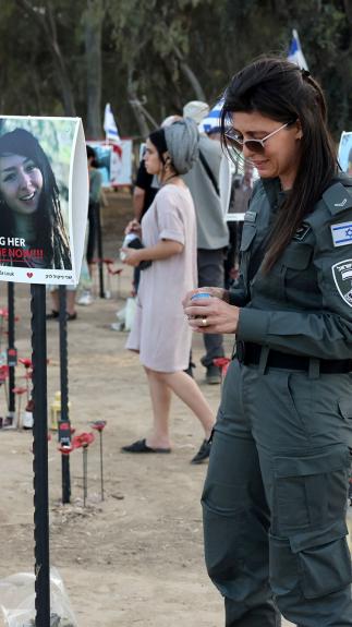 Iemand van de Israëlische security forces staat bij portretten van slachtoffers van de aanval