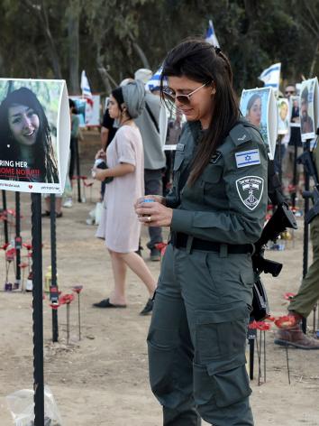 Iemand van de Israëlische security forces staat bij portretten van slachtoffers van de aanval