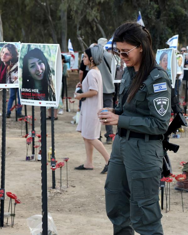 Iemand van de Israëlische security forces staat bij portretten van slachtoffers van de aanval