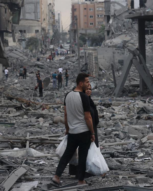 Palestijnen staan tussen de brokstukken na bombardementen op Gazastad