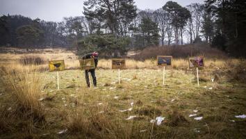 een natuurliefhebber plant borden met afbeelding van bedreigde soorten in een natuurgebied