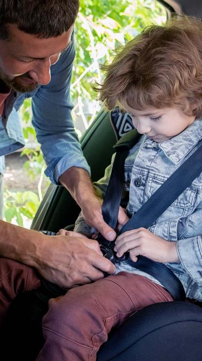 een vader doet de gordel van zijn zoon dicht