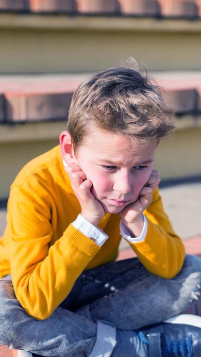 een jongen met z'n hoofd steunend op z'n handen