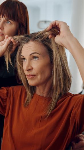 Vrouw kijkt naar grijze uitgroei bij de kapper