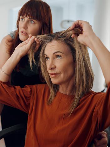 Vrouw kijkt naar grijze uitgroei bij de kapper