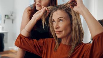 Vrouw kijkt naar grijze uitgroei bij de kapper