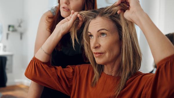 Vrouw kijkt naar grijze uitgroei bij de kapper