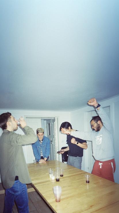 Vier vrienden spelen bierpong aan tafel tijdens een gezellige avond.