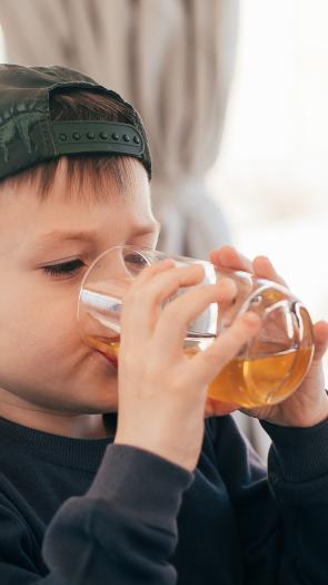 een kind drinkt uit een glas met appelsap