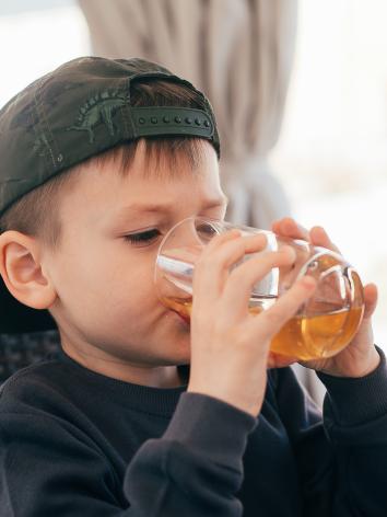een kind drinkt uit een glas met appelsap