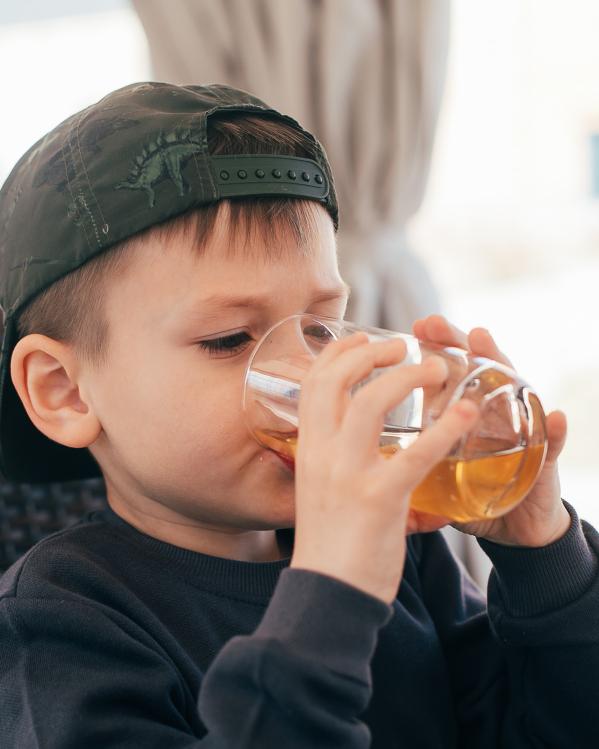 een kind drinkt uit een glas met appelsap