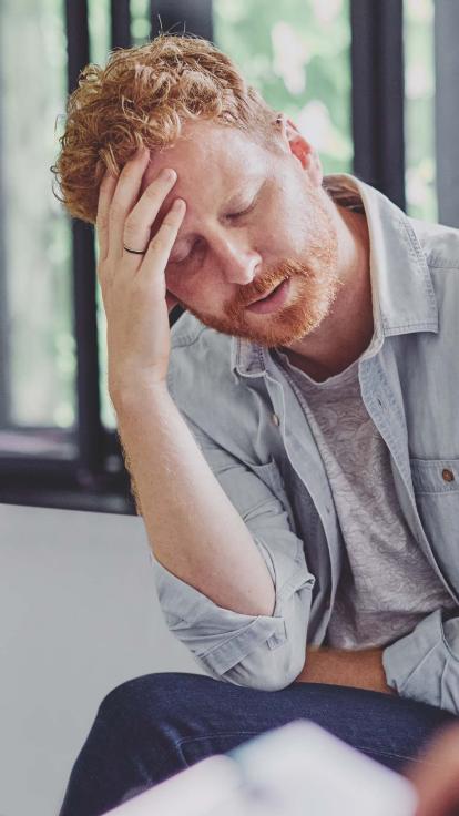 een man leunt met zijn voorhoofd op zijn hand