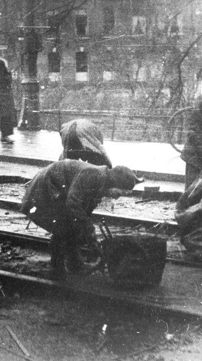 mensen pakken houtblokjes tussen tramrails weg