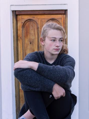 een tienermeisje staart buiten voor een huis voor zich uit