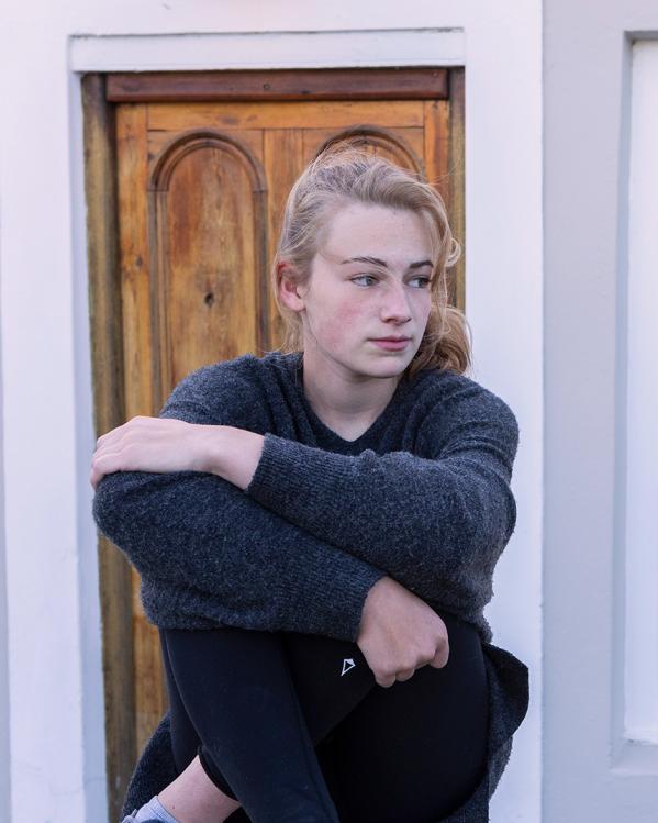 een tienermeisje staart buiten voor een huis voor zich uit