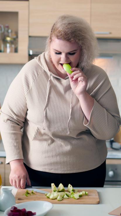 iemand eet een stuk van een appel in de keuken