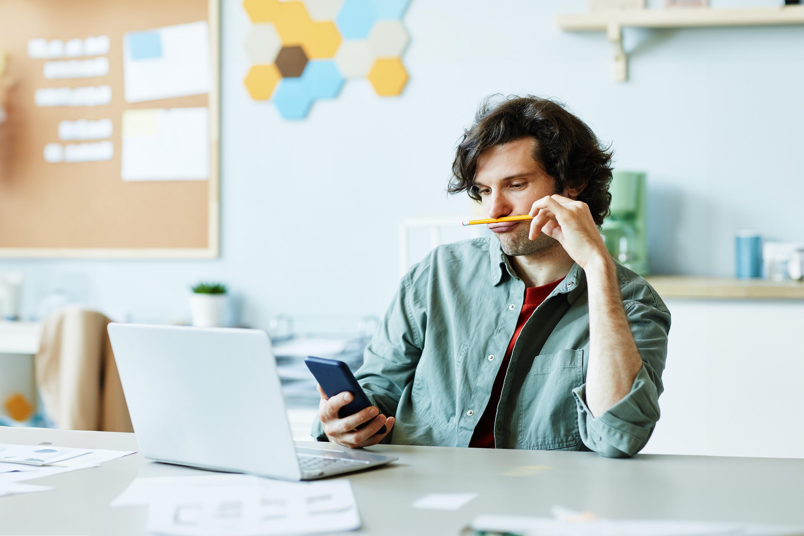 Man zit te spelen met een potlood en zijn telefoon tijdens werk 