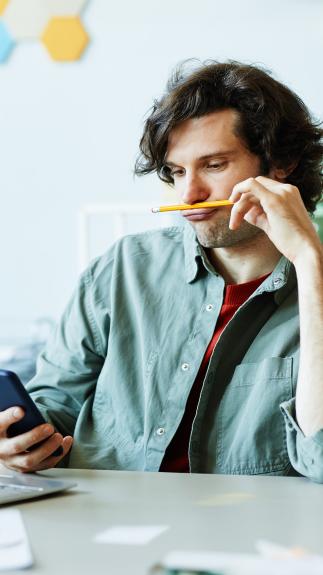 Man zit te spelen met een potlood en zijn telefoon tijdens werk 