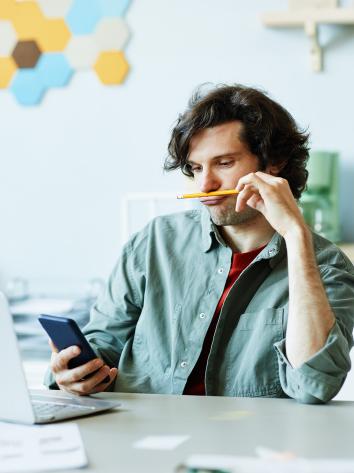 Man zit te spelen met een potlood en zijn telefoon tijdens werk 