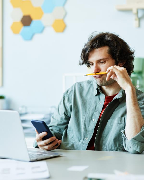 Man zit te spelen met een potlood en zijn telefoon tijdens werk