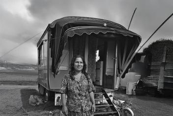  Een vrouw staat glimlachend voor haar woonwagen op een open terrein.