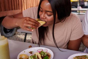 Een meisje neemt een hap van een taco met het kruid koriander