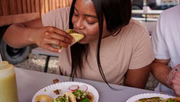 Een meisje neemt een hap van een taco met het kruid koriander