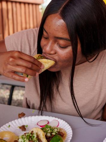 Een meisje neemt een hap van een taco met het kruid koriander