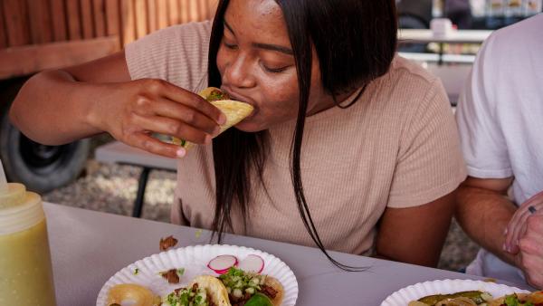 Een meisje neemt een hap van een taco met het kruid koriander