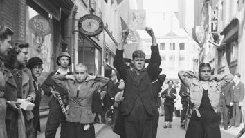 NSB'ers en kaalgeschoren 'moffenmeiden' lopen met handen omhoog door de stad