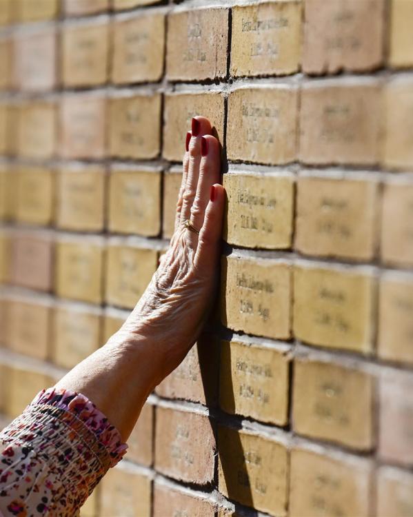 Een vrouw legt haar hand op het Nationaal Holocaust Namenmonument