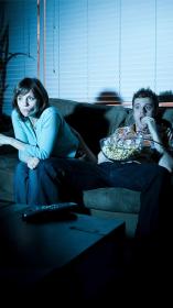 Twee mensen zitten op de bank tv te kijken met gespannen gezichten