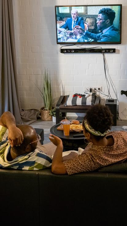 Achteraanzicht van twee mensen die tv kijken met snacks