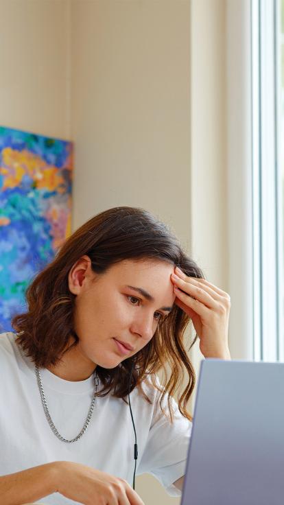 Vrouw kijkt geïnteresseerd naar een laptop 