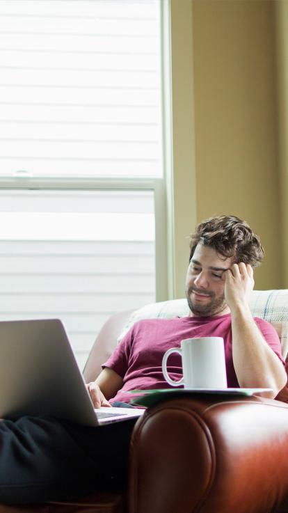 Jongen op luie stoel kijkt naar serie op zijn laptop