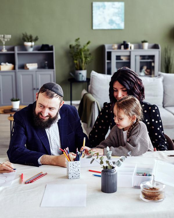 Een Joodse familie met drie kinderen zit aan tafel te kleuren