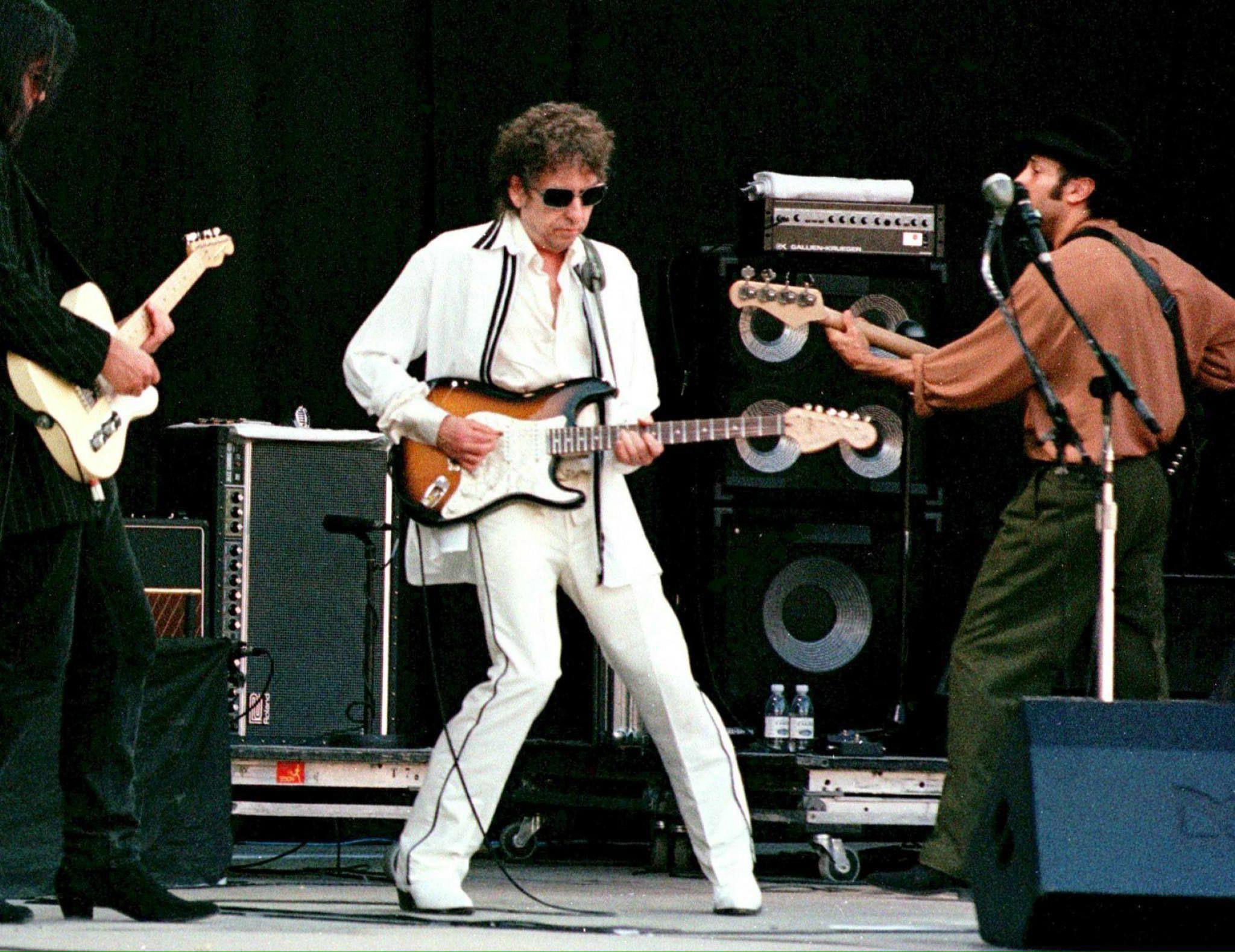Bob Dylan speelt gitaar met twee bandleden op een podium in 1998