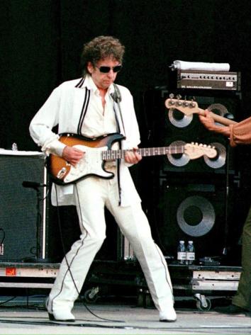 Bob Dylan speelt gitaar met twee bandleden op een podium in 1998
