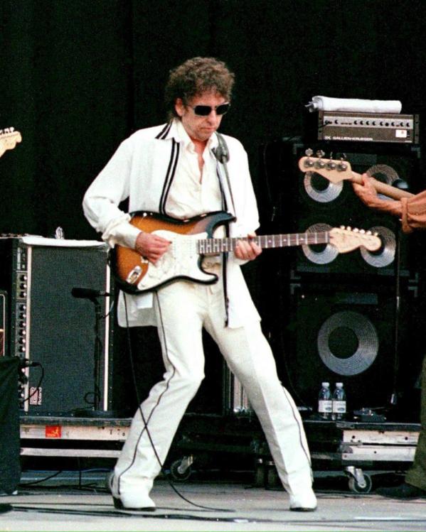 Bob Dylan speelt gitaar met twee bandleden op een podium in 1998