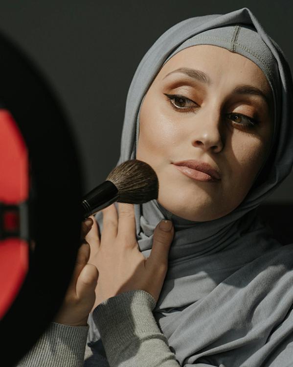 een vrouw maakt zich op voor een selfie-camera van mobiel met ringlicht eromheen