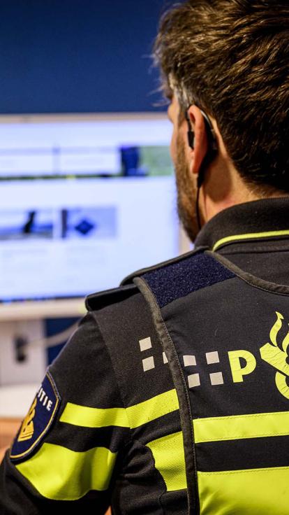 Een politieagent zit achter zijn computer.