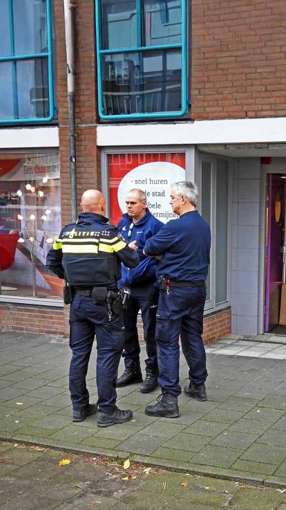 Een politieagent staat op straat iemand te bevragen.