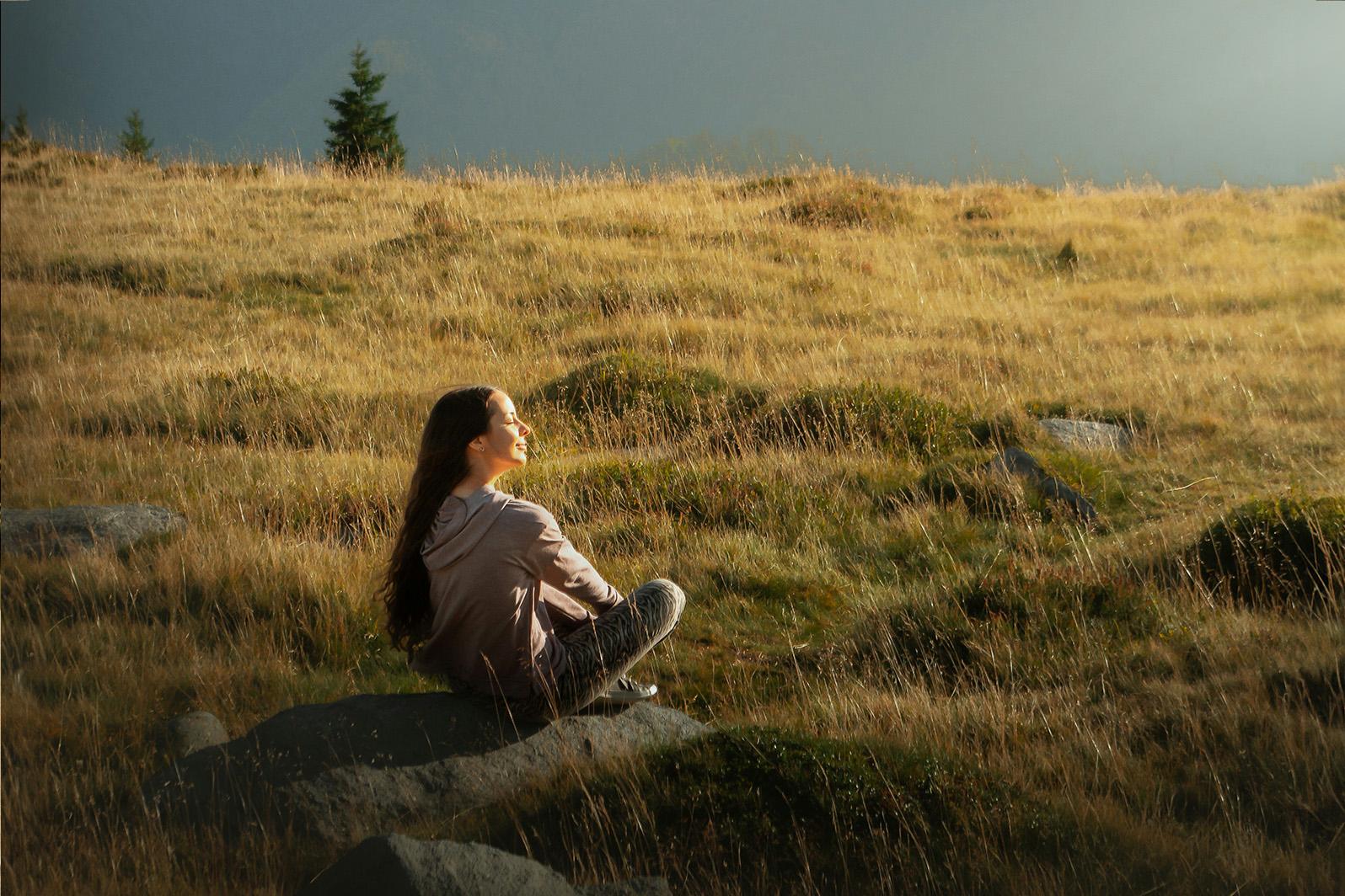 Meisje zit in grasveld in de zon en kijkt naar de lucht