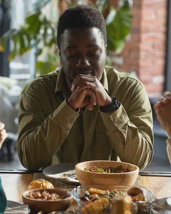 Een familie aan het bidden voor het eten