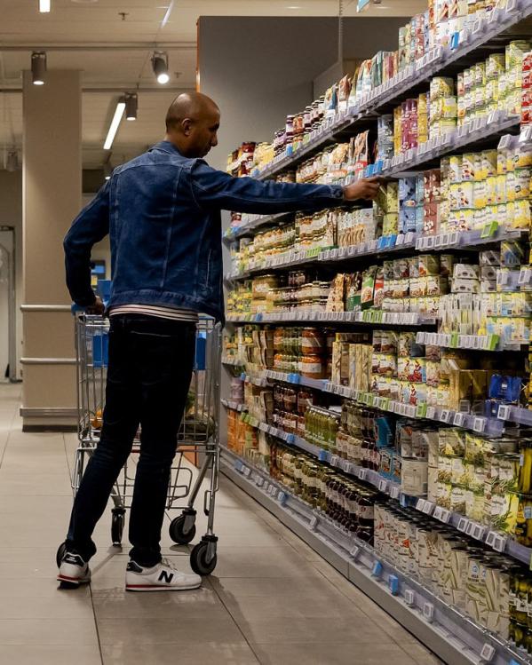 Een klant pakt iets uit een schap in de supermarkt.