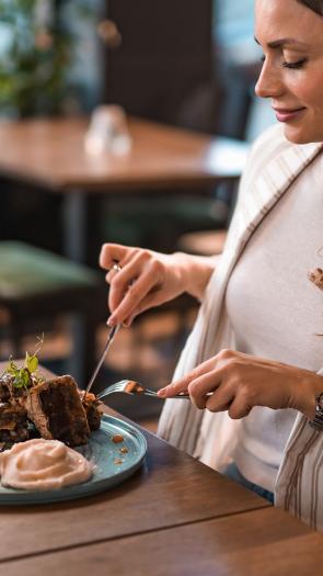 Vrouw in restaurant snijdt in stukjes biefstuk